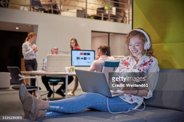 young woman working in modern creative office, usine laptop and headphones - businesswear stock pictures, royalty-free photos & images