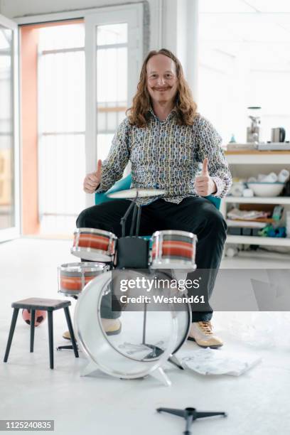 portrait of confident man sitting at toy drums - weird hobbies stock pictures, royalty-free photos & images