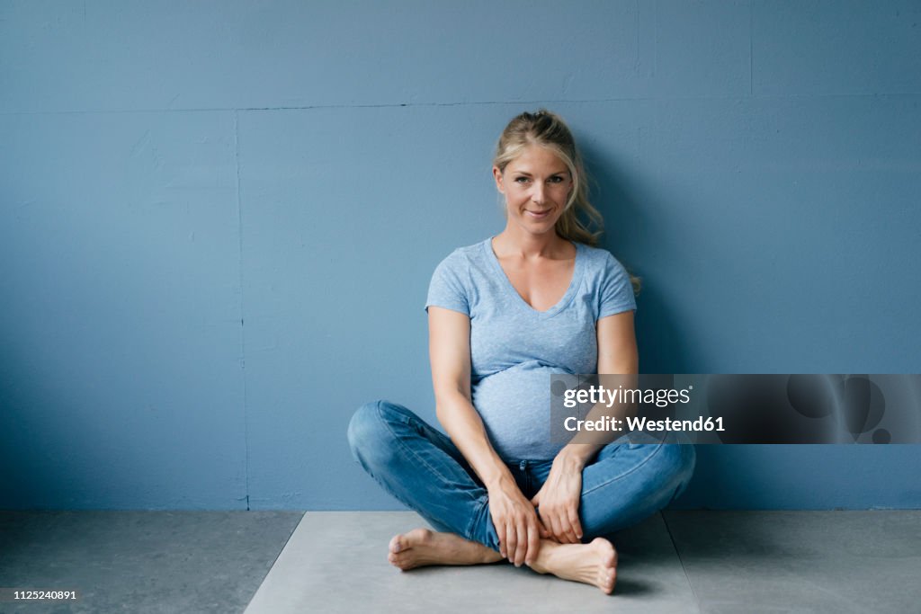 Portrait of smiling pregnant woman sitting on the floor