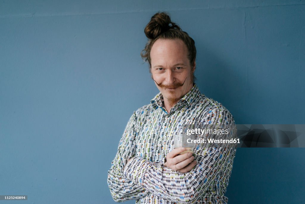 Portrait of man with moustache standing at blue wall