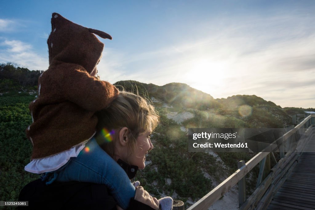 Mother and baby girl, sitting on her shoulders, on the way to Boulders beach