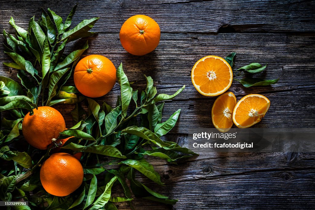 Orange branch with orange fruits shot on rustic wooden table