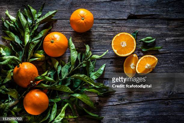 orange branch with orange fruits shot on rustic wooden table - orange stock pictures, royalty-free photos & images