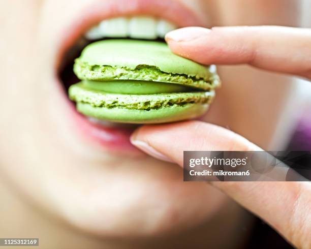 close-up of a woman eating a macaroon - macarons fotografías e imágenes de stock