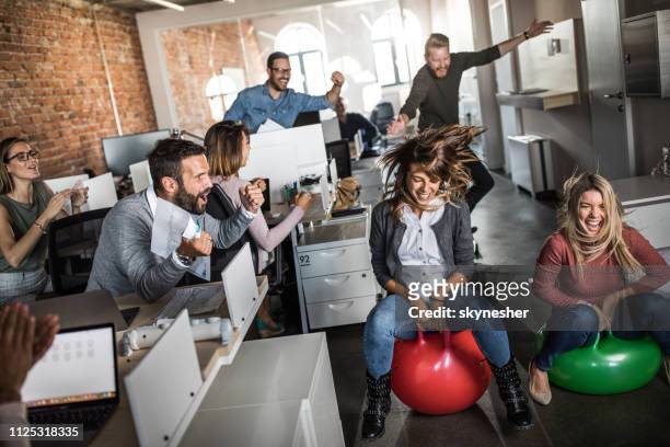 cheerful colleagues having fun during space hopper at corporate office. - hoppity horse stock pictures, royalty-free photos & images