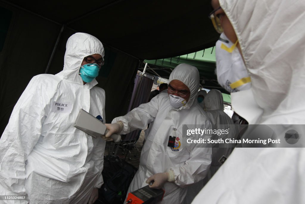 A rescue worker from Auxiliary Medical Services wearing white environmental suits scan a police officer for radiation near Ma Liu Shui Ferry Pier during the Daya Bay Contingency Plan exercise in Hong Kong on April 26, 2012. The Hong Kong government conduc