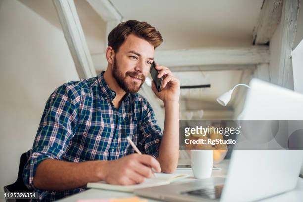 hombre escribiendo y hablando por teléfono - búsqueda de trabajo fotografías e imágenes de stock