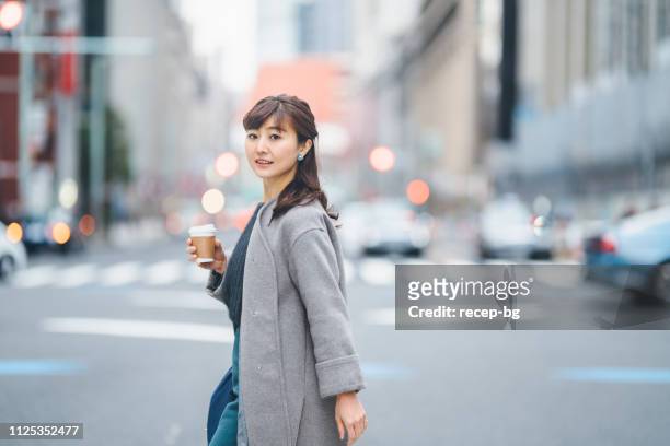 コーヒーを押しながら交差道路で実業家 - 女性　日本 ストックフォトと画像