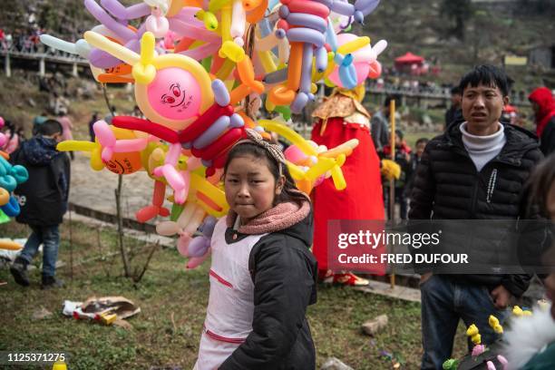 This photo taken on February 14, 2019 shows a girl selling balloons at the annual flower festival or 'Tiaohuajie' in the village of Longjia in...