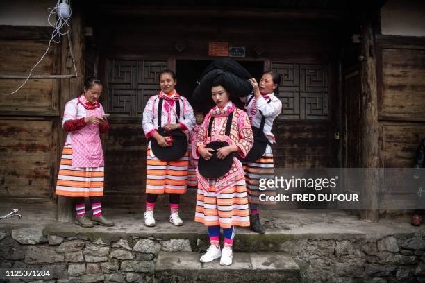 This photo taken on February 14, 2019 shows a girl from the Long Horn Miao, a branch of the Miao ethnic minority group, getting her wig set prior to...