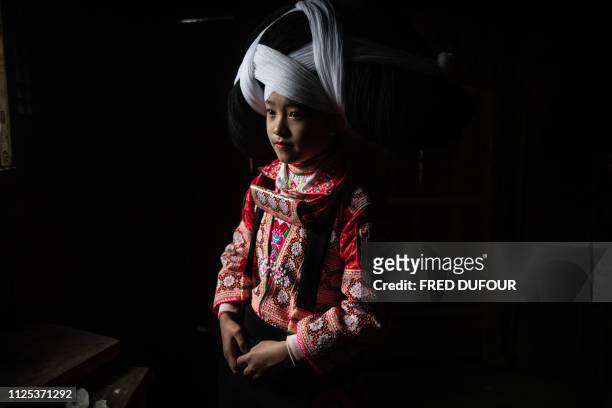 This photo taken on February 14, 2019 shows a girl from the Long Horn Miao, a branch of the Miao ethnic minority group, posing for a photo in her wig...