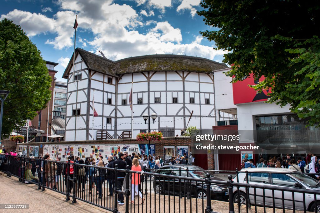 Tourists and locals walking beside Shakespeare's Globe theatre in London, England.