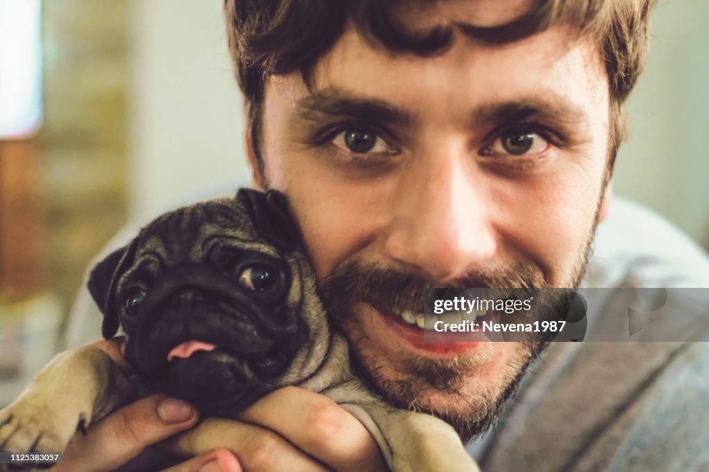 Young Man And Puppy Pug