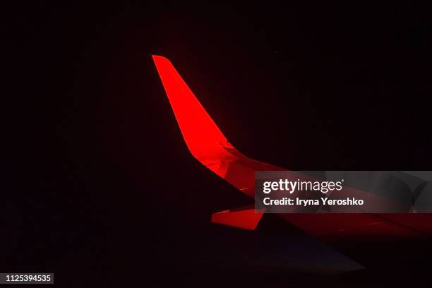 view of a airplane wing at night during a red eye flight - red plane stock pictures, royalty-free photos & images