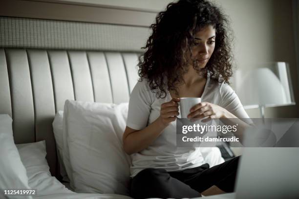 junge frau mit ihrem laptop auf dem bett - arab watching tv stock-fotos und bilder