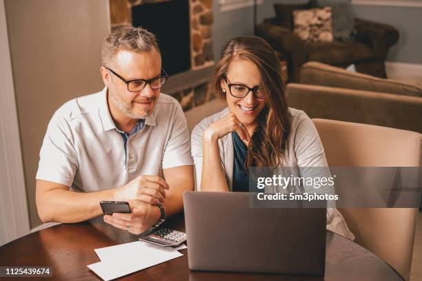 couple using laptop at kitchen table financial planning - investing for retirement imagens e fotografias de stock