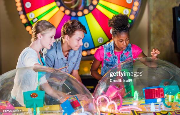 multi-ethnischen teenager freunde arcade-spiele spielen - glücksrad stock-fotos und bilder