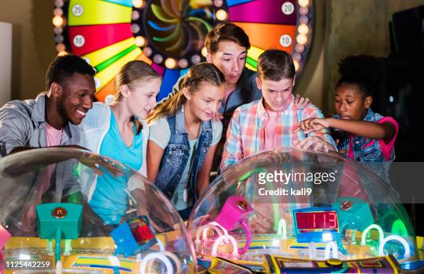 multi-ethnic teenage friends playing arcade games - arcade stock pictures, royalty-free photos & images