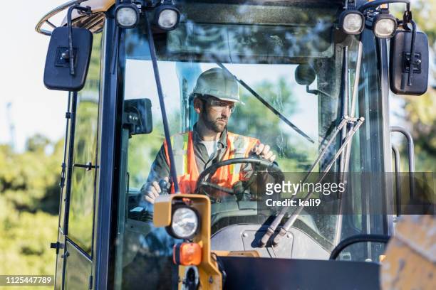 construction worker operating a backhoe - construction vehicle stock pictures, royalty-free photos & images