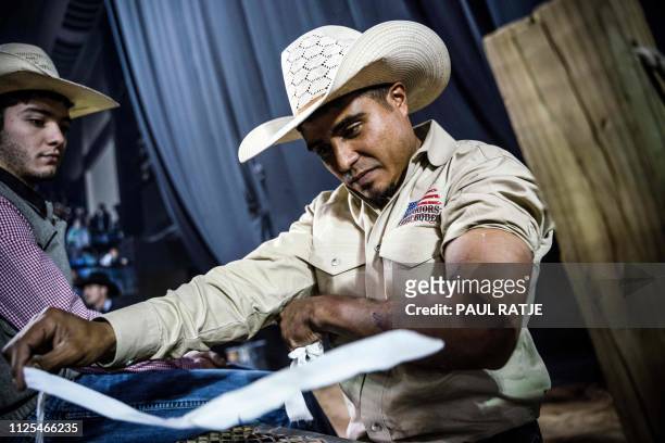 Texas Bullrider Juan Alonzo is pictured taking off wrapping from his arm during the Tuff Hedeman Bull Riding Tour at the El Paso County Colosseum on...