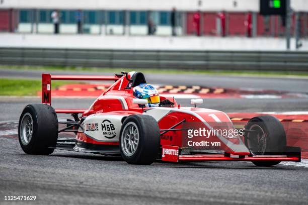 rot, einsitzigen rennwagen auf der strecke - formula 1 car stock-fotos und bilder