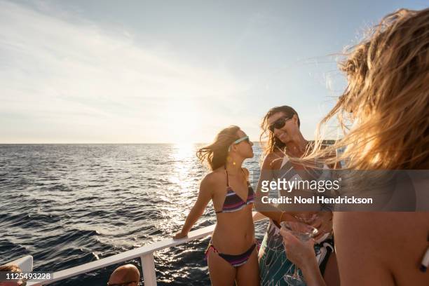 mother and daughter smiling to one another on boat deck - catamaran sailing stock-fotos und bilder