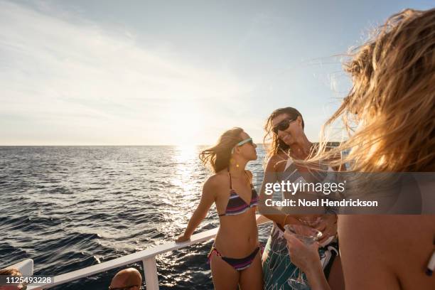 mother and daughter smiling to one another on boat deck - catamaran sailing stock pictures, royalty-free photos & images