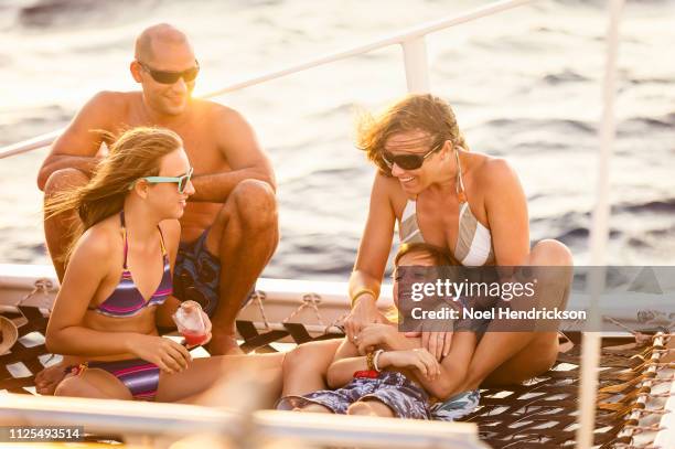 family bonding on boat deck at sunset - catamaran sailing stock-fotos und bilder
