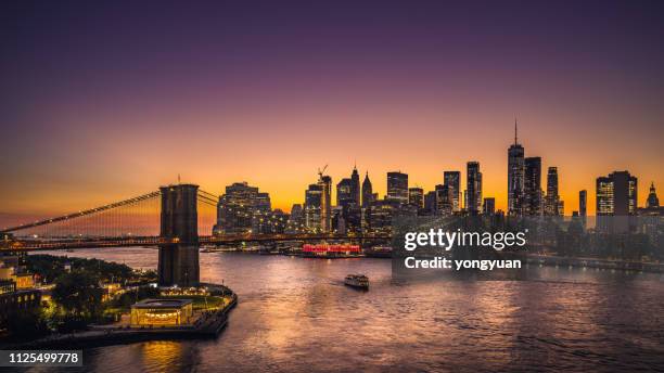 new york city skyline en brooklyn bridge bij zonsondergang - nyc skyline night stockfoto's en -beelden