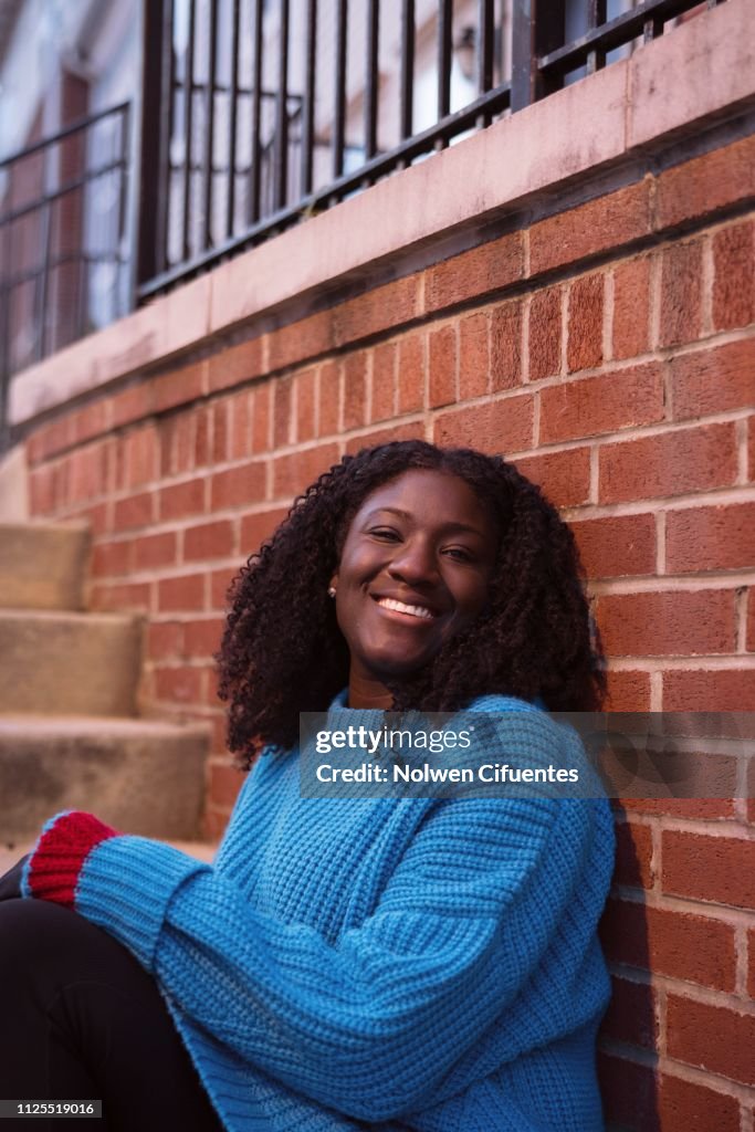 Young woman smiling against brick wall