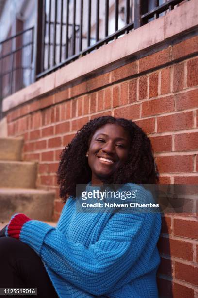 Young woman smiling against brick wall