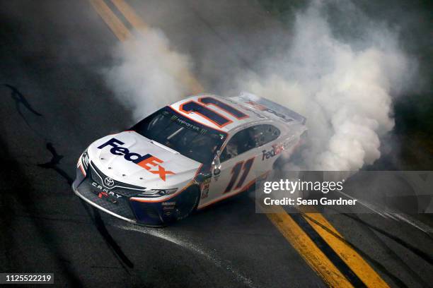 Denny Hamlin, driver of the FedEx Express Toyota, celebrates with a burnout after winning the Monster Energy NASCAR Cup Series 61st Annual Daytona...