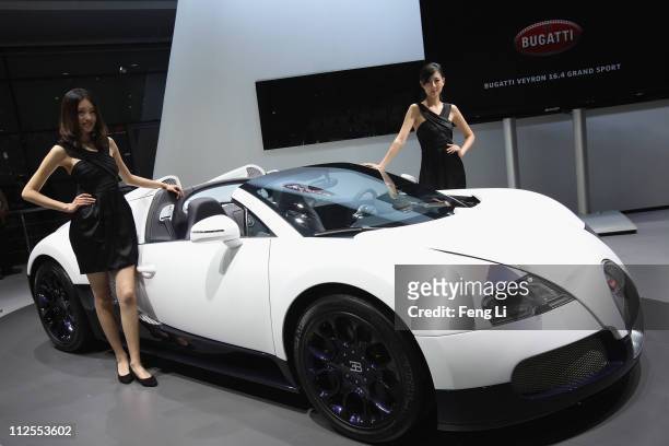 Two models pose beside the Bugatti 16.4 Super Sport during the media day of the Shanghai International Automobile Industry Exhibition at Shanghai New...