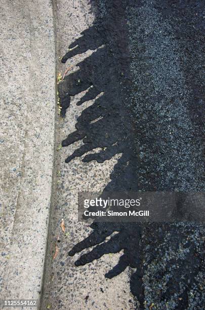 bitumen that has run into a concrete kerb after road resurfacing - rinnstein stock-fotos und bilder