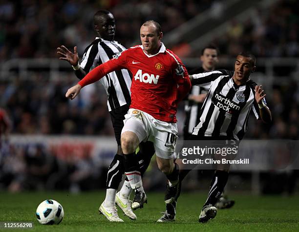 Wayne Rooney of Manchester United is challenged by Cheik Tiote and Danny Simpson of Newcastle United during the Barclays Premier League match between...