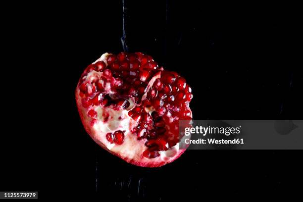 sliced pomegranate in front of black background - verführung stock-fotos und bilder