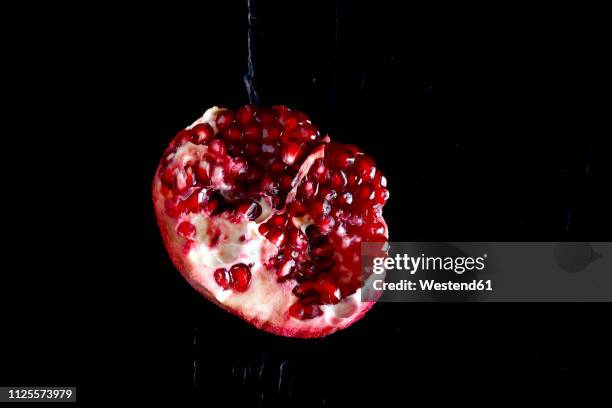 sliced pomegranate in front of black background - pomegranate seed stock pictures, royalty-free photos & images