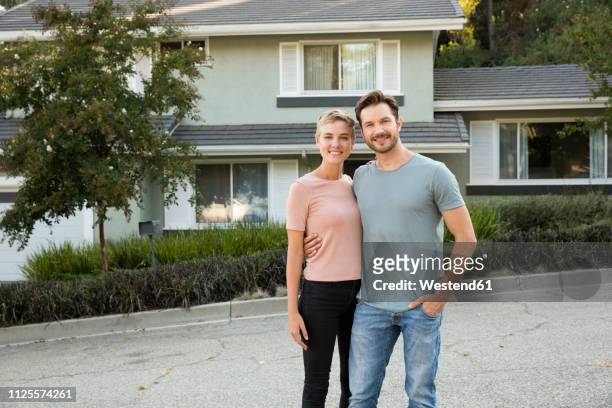 portrait of smiling couple in front of their home - house front bildbanksfoton och bilder