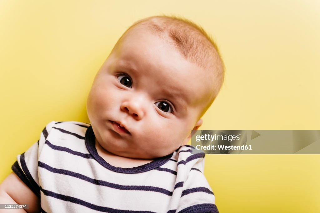 Portrait of sceptical baby girl in front of yellow background