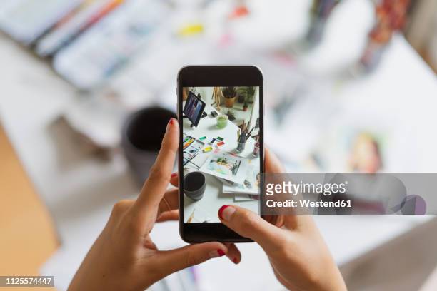illustrator's hands taking photo of work desk in atelier with smartphone, close-up - ostasiatischer abstammung stock-grafiken, -clipart, -cartoons und -symbole