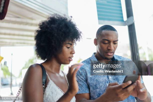 usa, florida, miami beach, young couple using cell phone in the city - angry on phone photos et images de collection