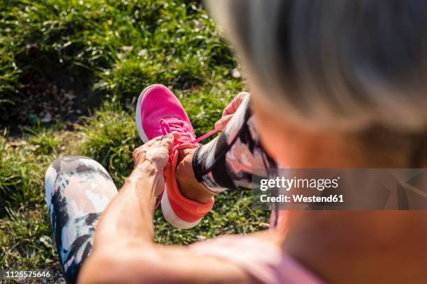 sportive senior woman tying her shoes - pink shoe bildbanksfoton och bilder