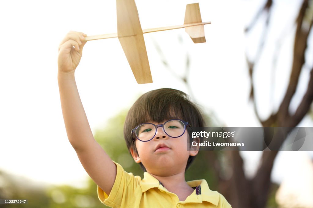 5 years old young boy throwing toy aeroplane.