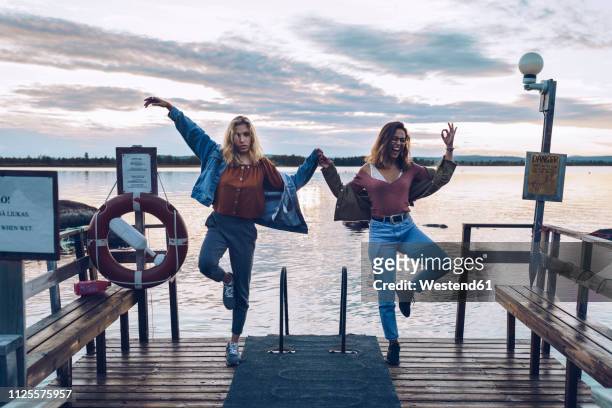 two girl friends standing on one leg on a pier at lake inari, finland - inari finland stock pictures, royalty-free photos & images
