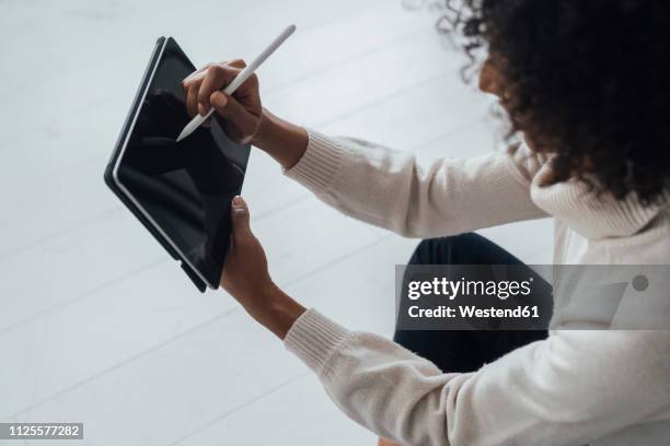 disigner sitting on ground of her home office, using digital tablet - digitized pen stock pictures, royalty-free photos & images