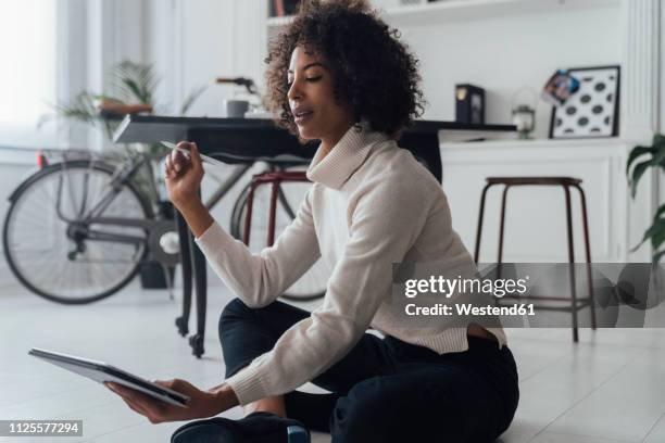 disigner sitting on ground of her home office, using digital tablet - three quarter length stock pictures, royalty-free photos & images