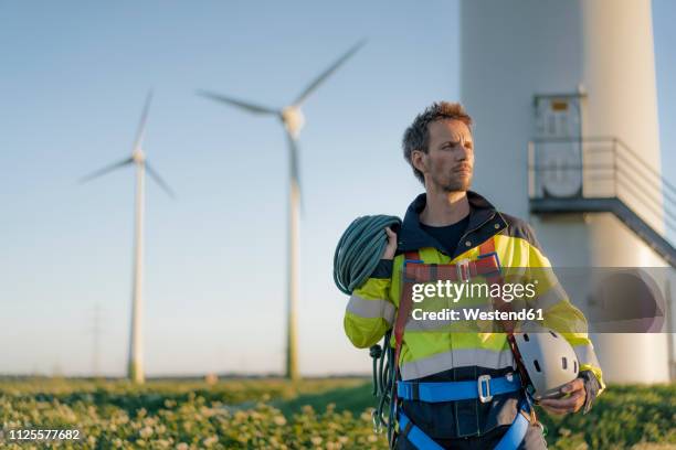 technician standing at a wind farm with climbing equipment - rope access technician stock pictures, royalty-free photos & images