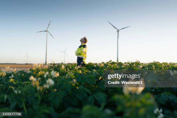 engineer standing in a field at a wind farm - protect environment stock pictures, royalty-free photos & images