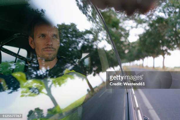man in protective workwear in a car at country road - man car stock pictures, royalty-free photos & images