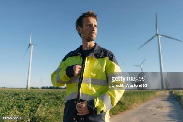 portrait of an engineer on field path at a wind farm - green coat foto e immagini stock